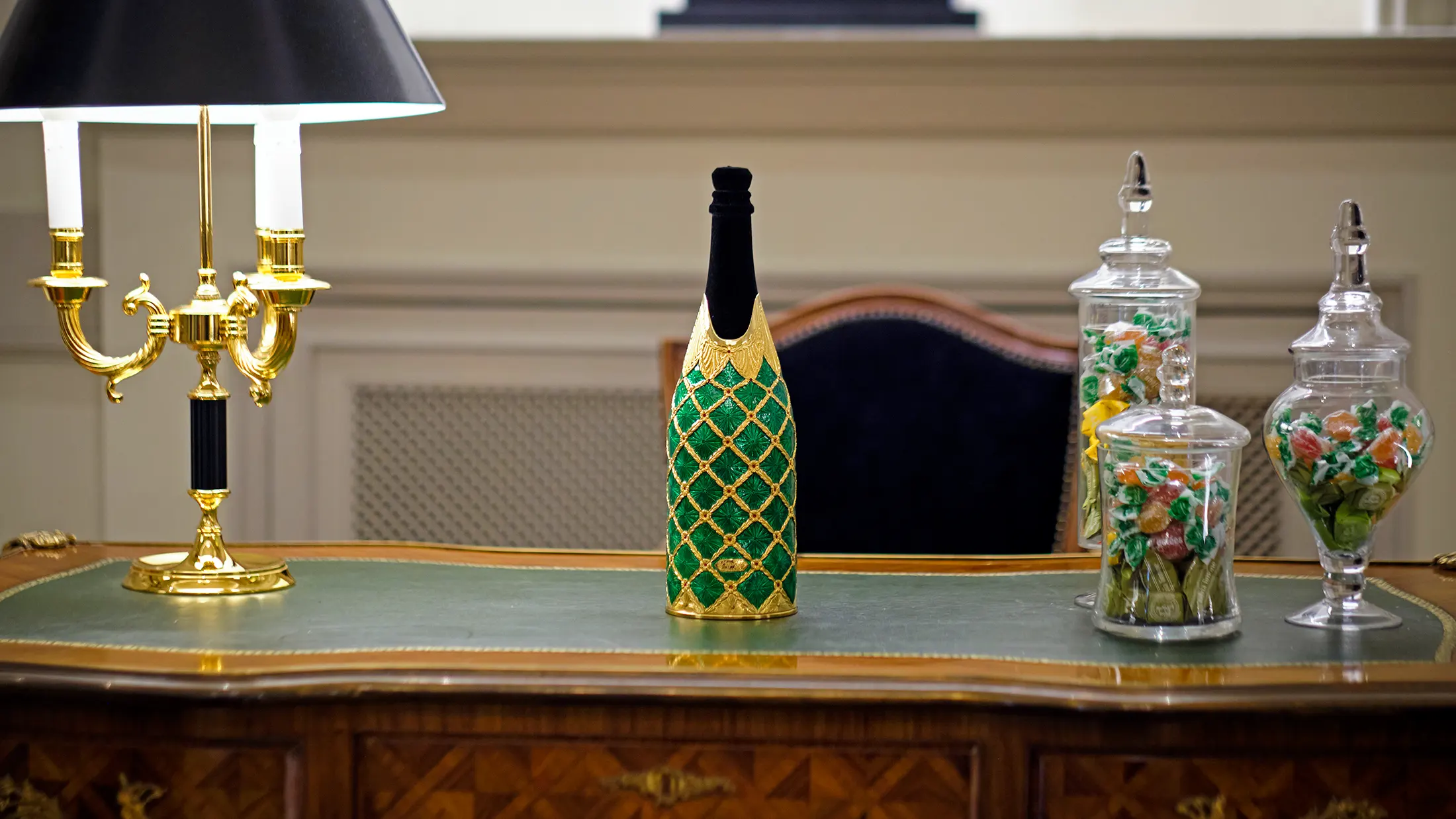 Lifestyle photograph of a green enameled and gold bottle cover by K-Over in an ambient setting – product photography by Memento Agency