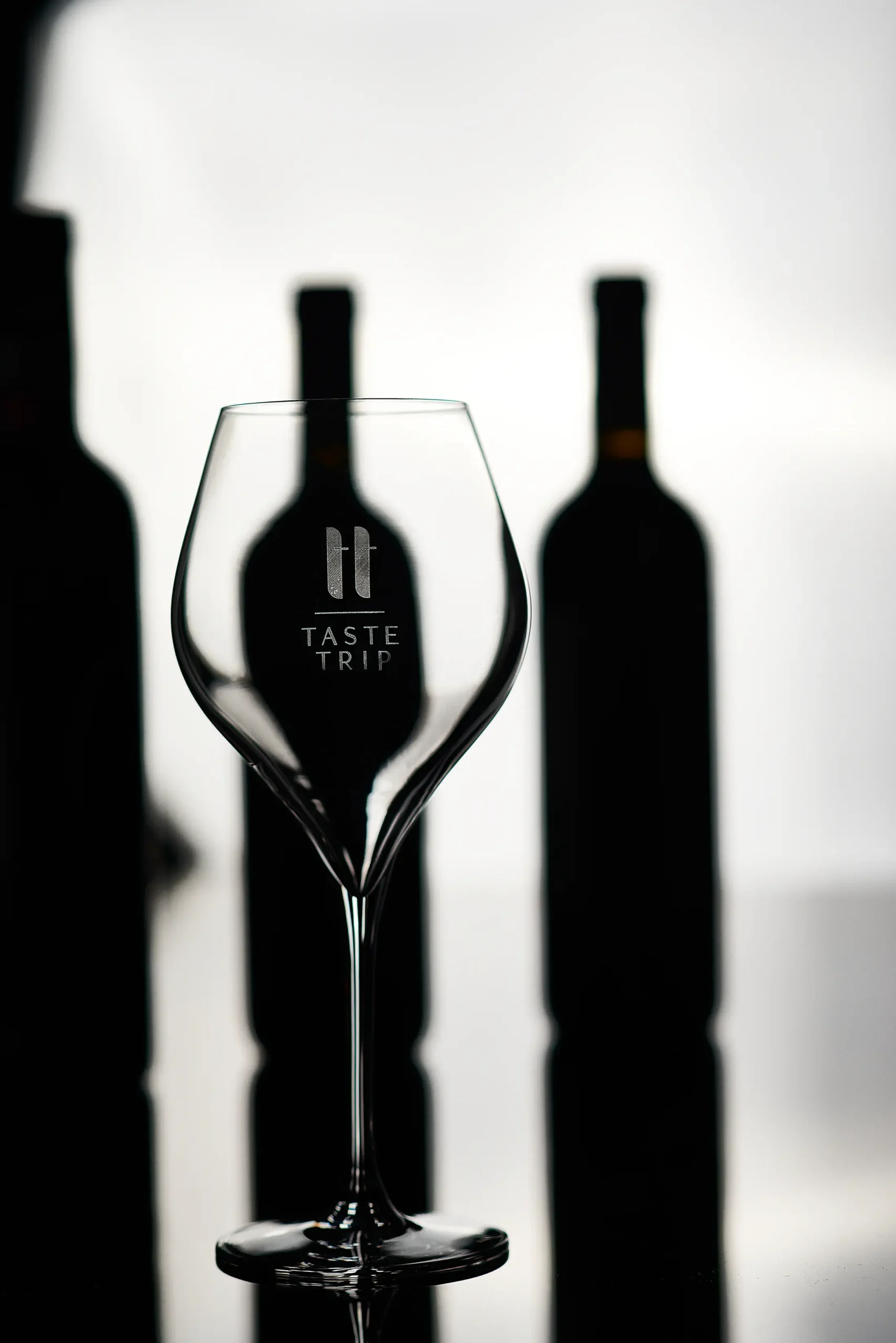 Low key still life photography of a wine glasse and bottles on a black background – studio setup, backlit photo