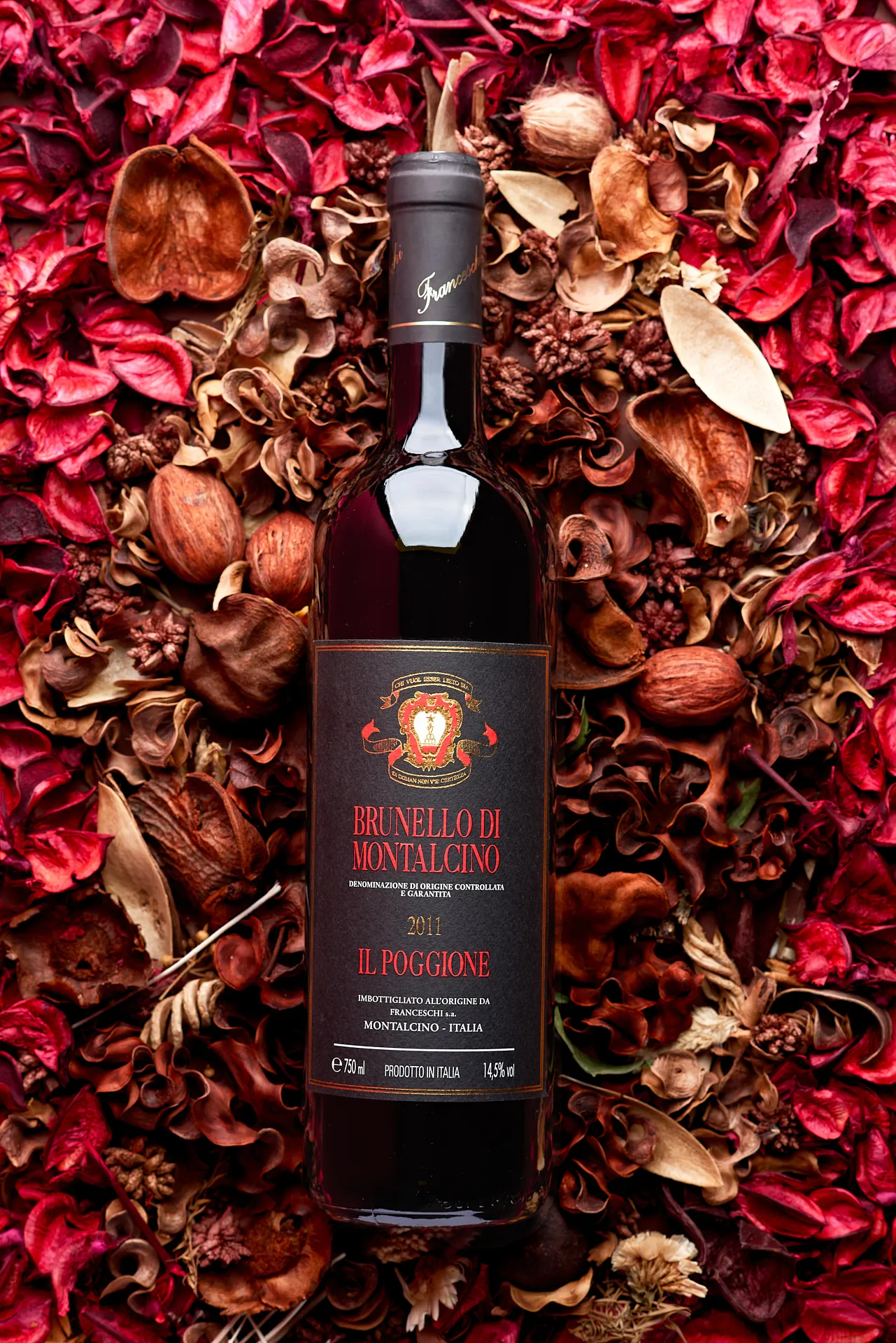 Ambient still life close-up of Brunello di Montalcino wine bottle lying on potpourri – elegant Tuscan wine product photography