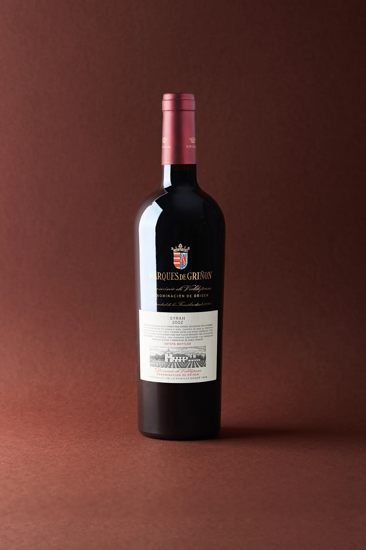 Still life photo of Syrah wine bottle from Marques de Grinon on brown background – elegant Spanish wine product photography