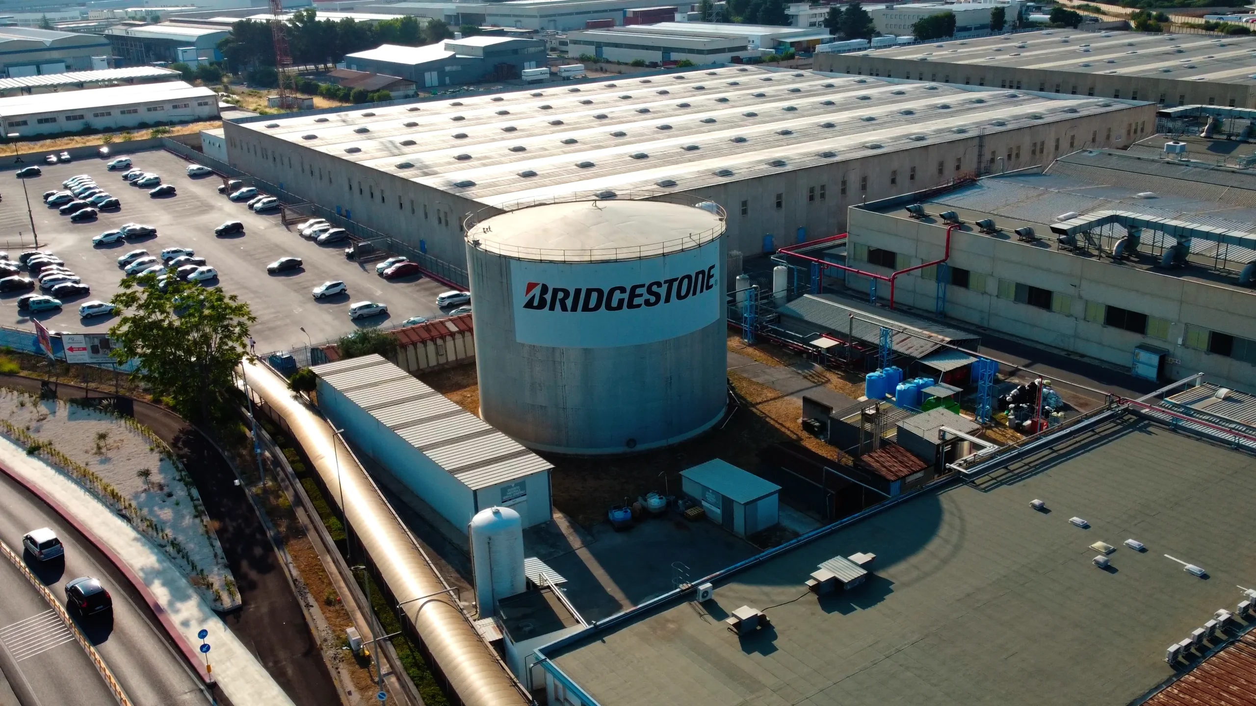 Drone video frame of the Bridgestone Italia facility with the company logo visible on the rooftops, captured for Kiwitron by Memento Agency – industrial aerial promotional footage