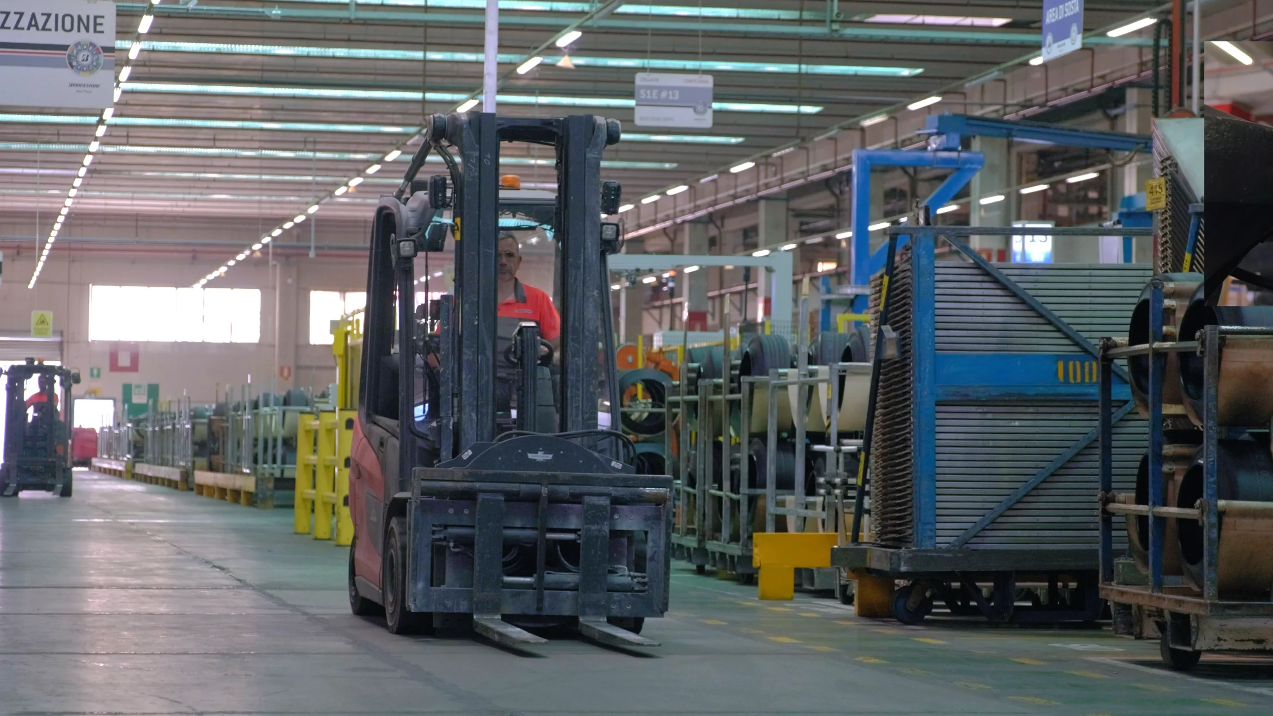 Video frame of a man driving a forklift inside the Bridgestone Italia facility, captured for Kiwitron by Memento Agency – industrial promotional footage