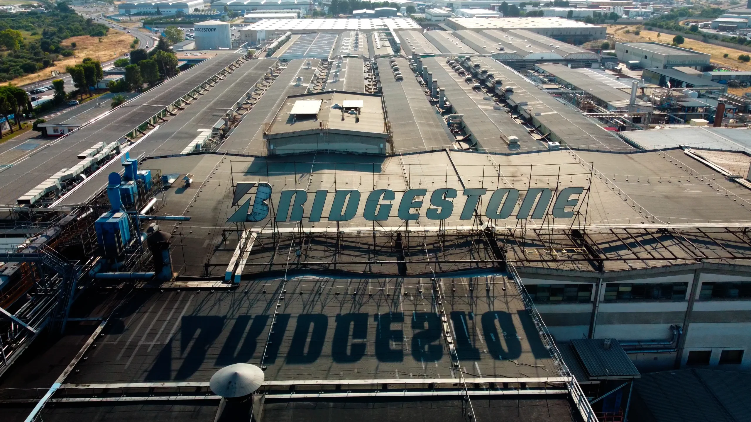 Drone video frame of the Bridgestone Italia facility with the company logo visible on the rooftops, captured for Kiwitron by Memento Agency – industrial aerial promotional footage